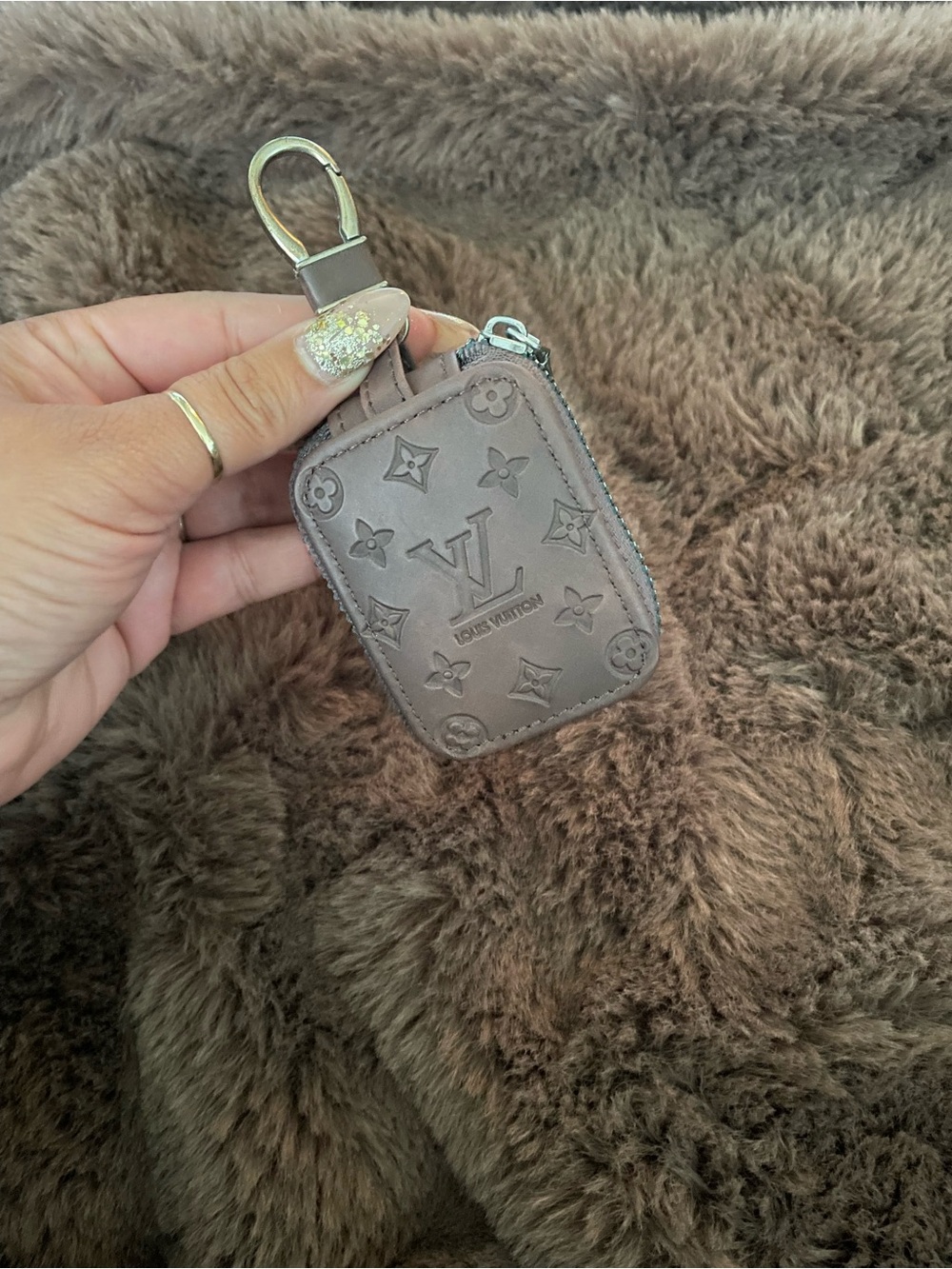 Monogram airpod case in Taupe/brown with Hardware to clip on bag.